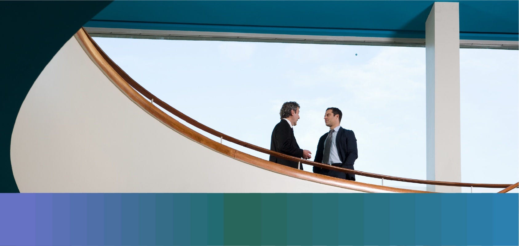 Two men in business suits chat on a balcony