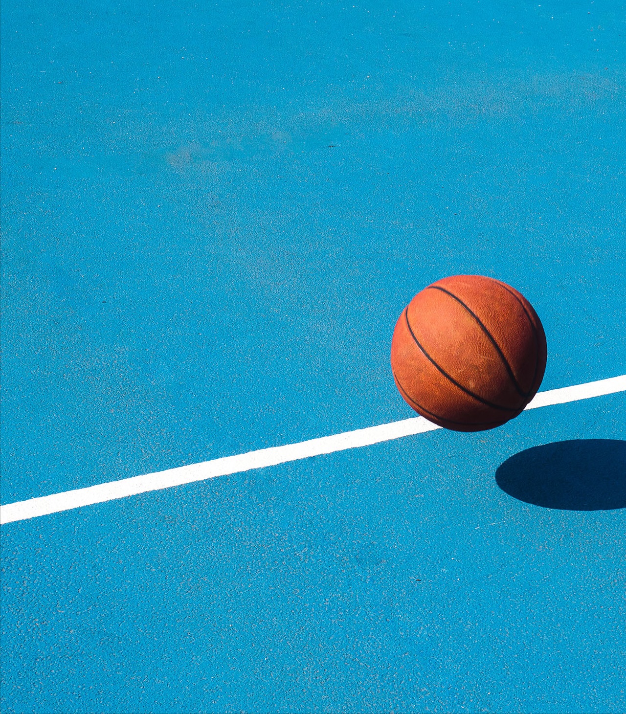 Basketball bouncing on a blue court