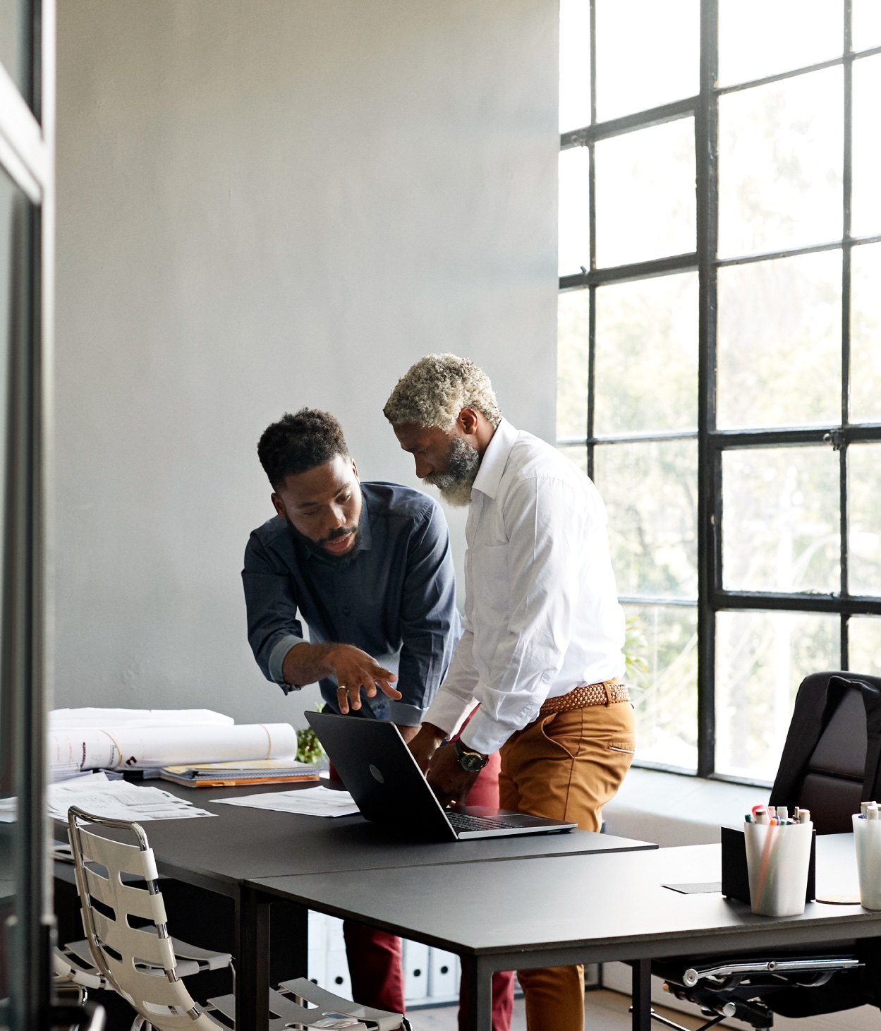 Young employee collaborates with an older teammate on a project. 