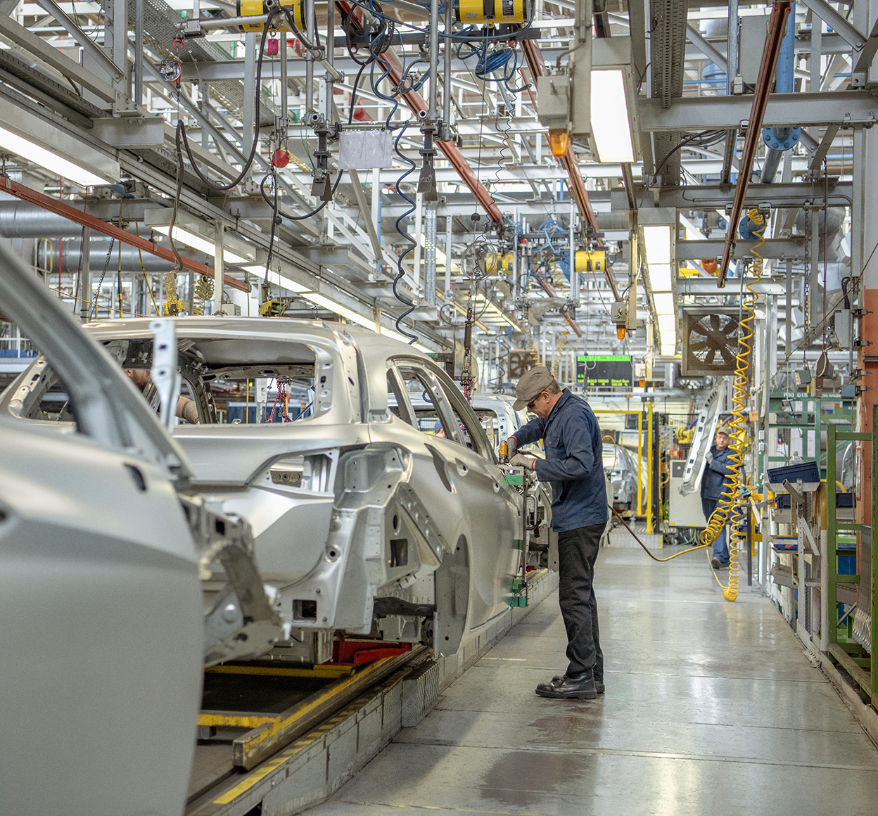 Factory worker operates on a automotive assembly line