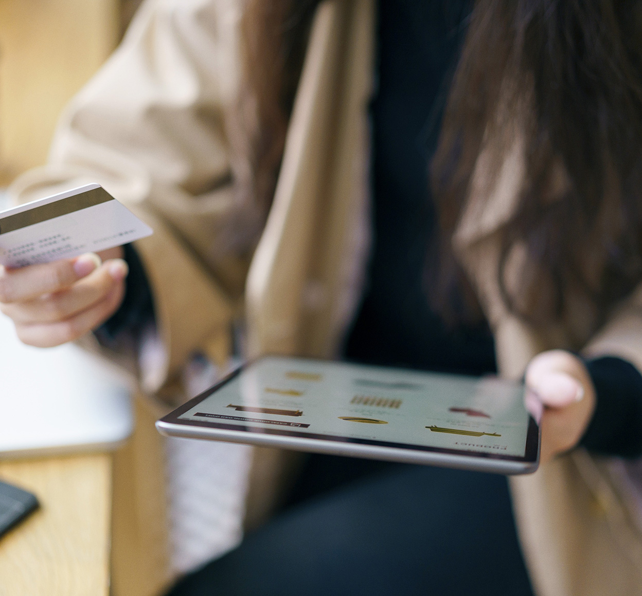 Woman holds her credit card as she shops online with a tablet computer