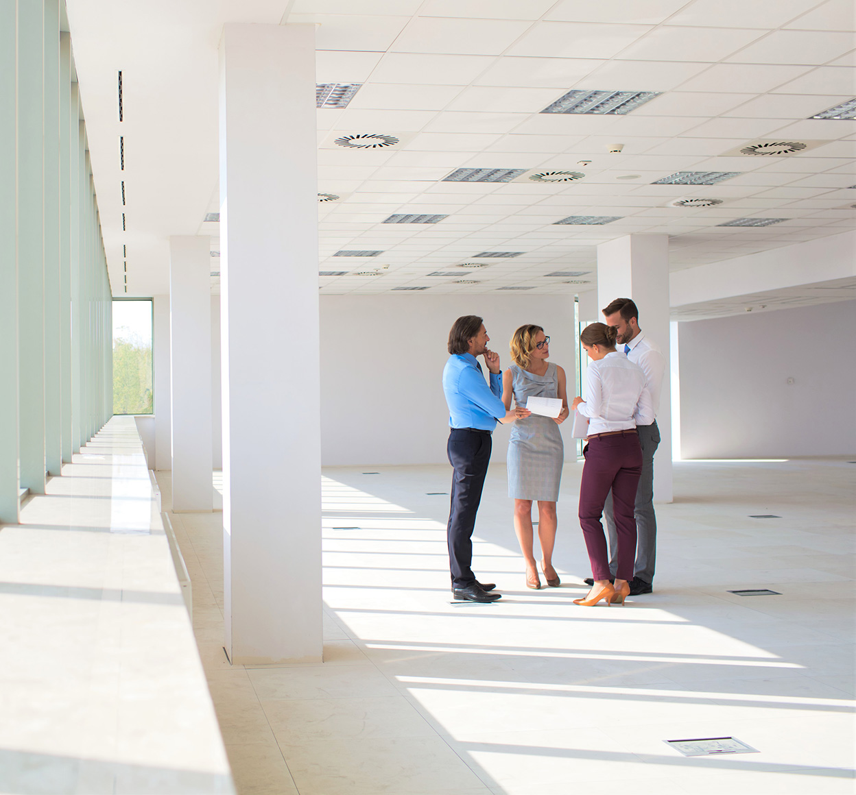 Full length of business colleagues standing while discussing at new office