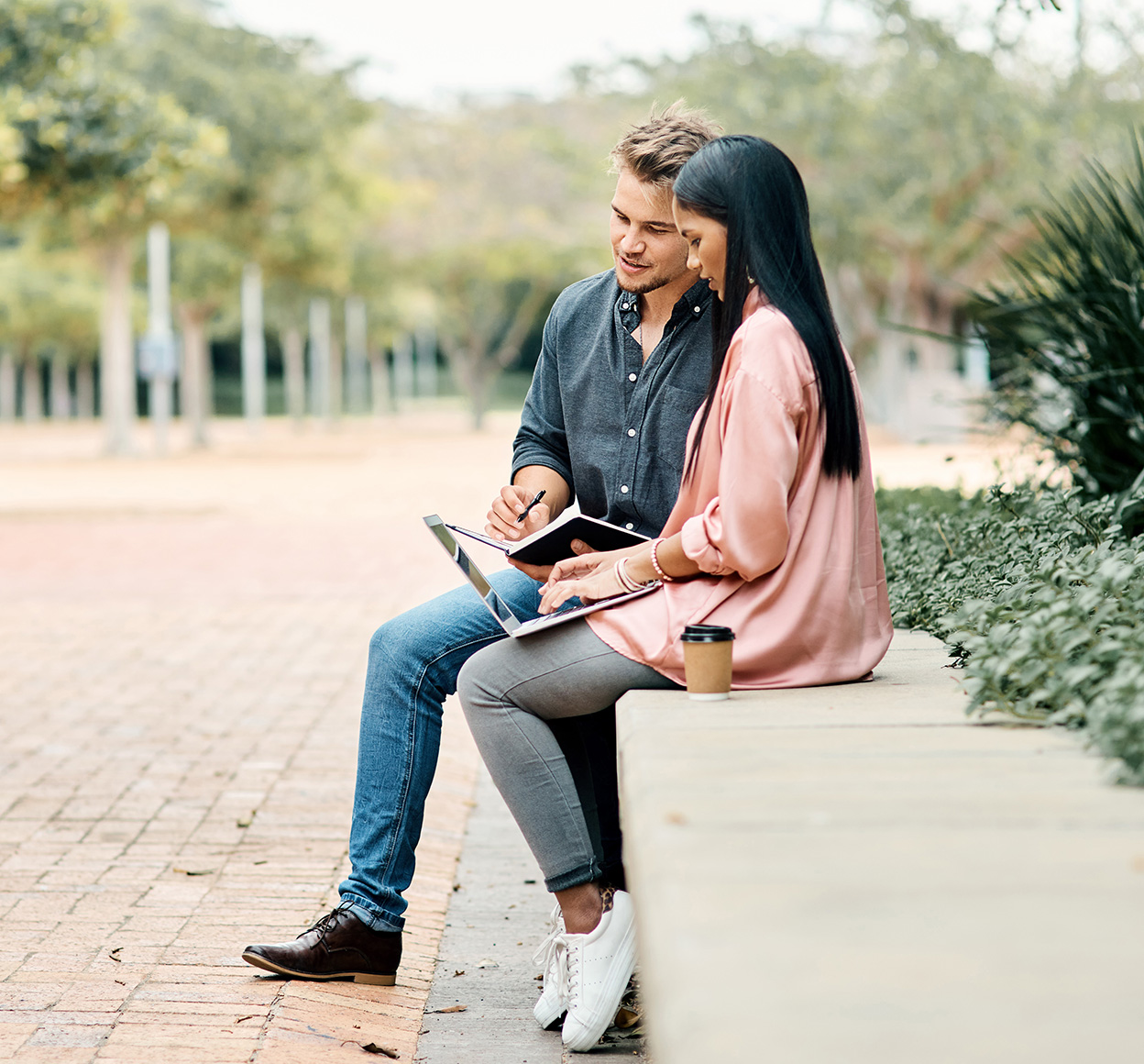 man and woman sitting in park looking at a mobile device