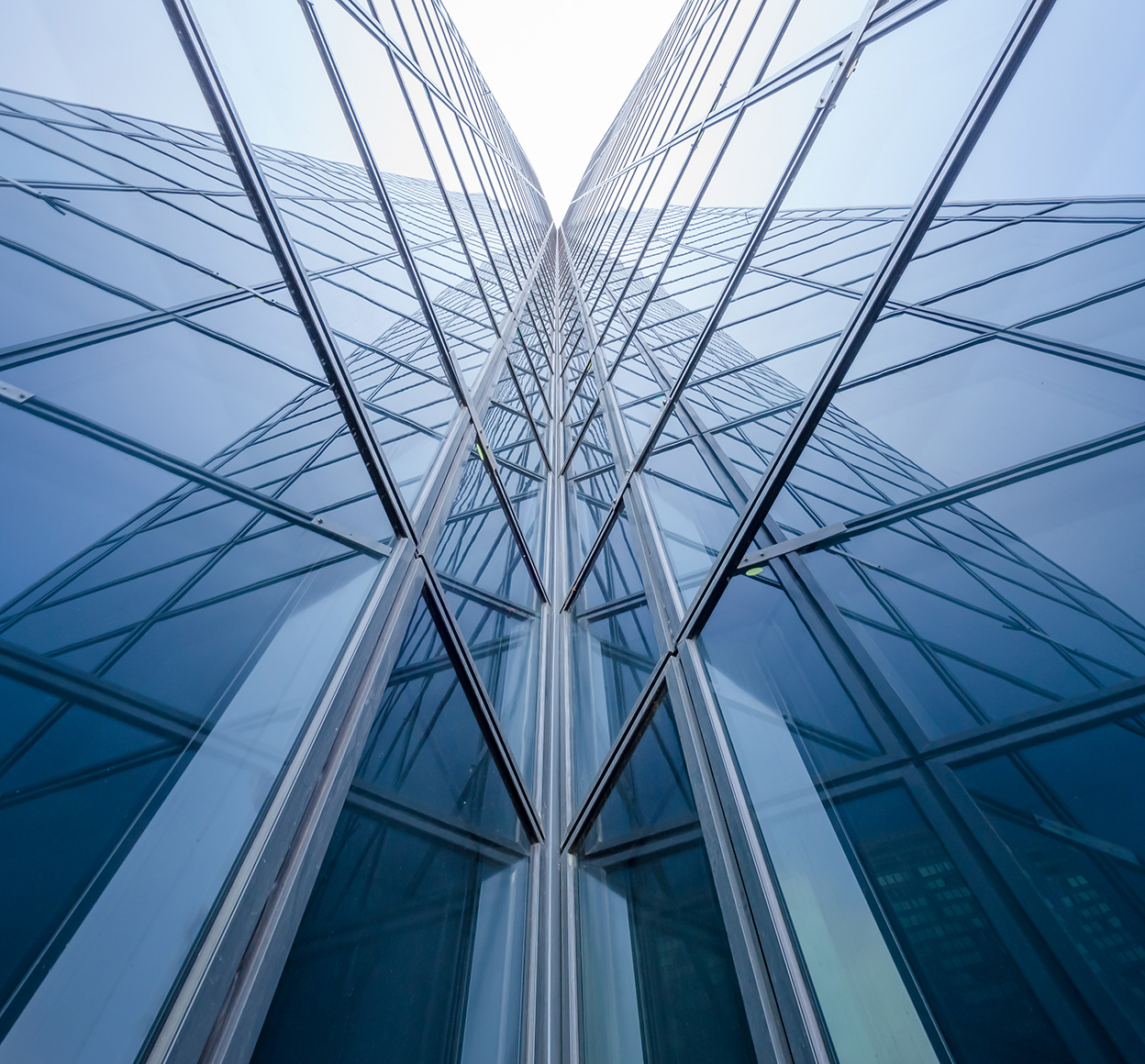 Low-angle photo of two modern glass building walls intersecting at a corner