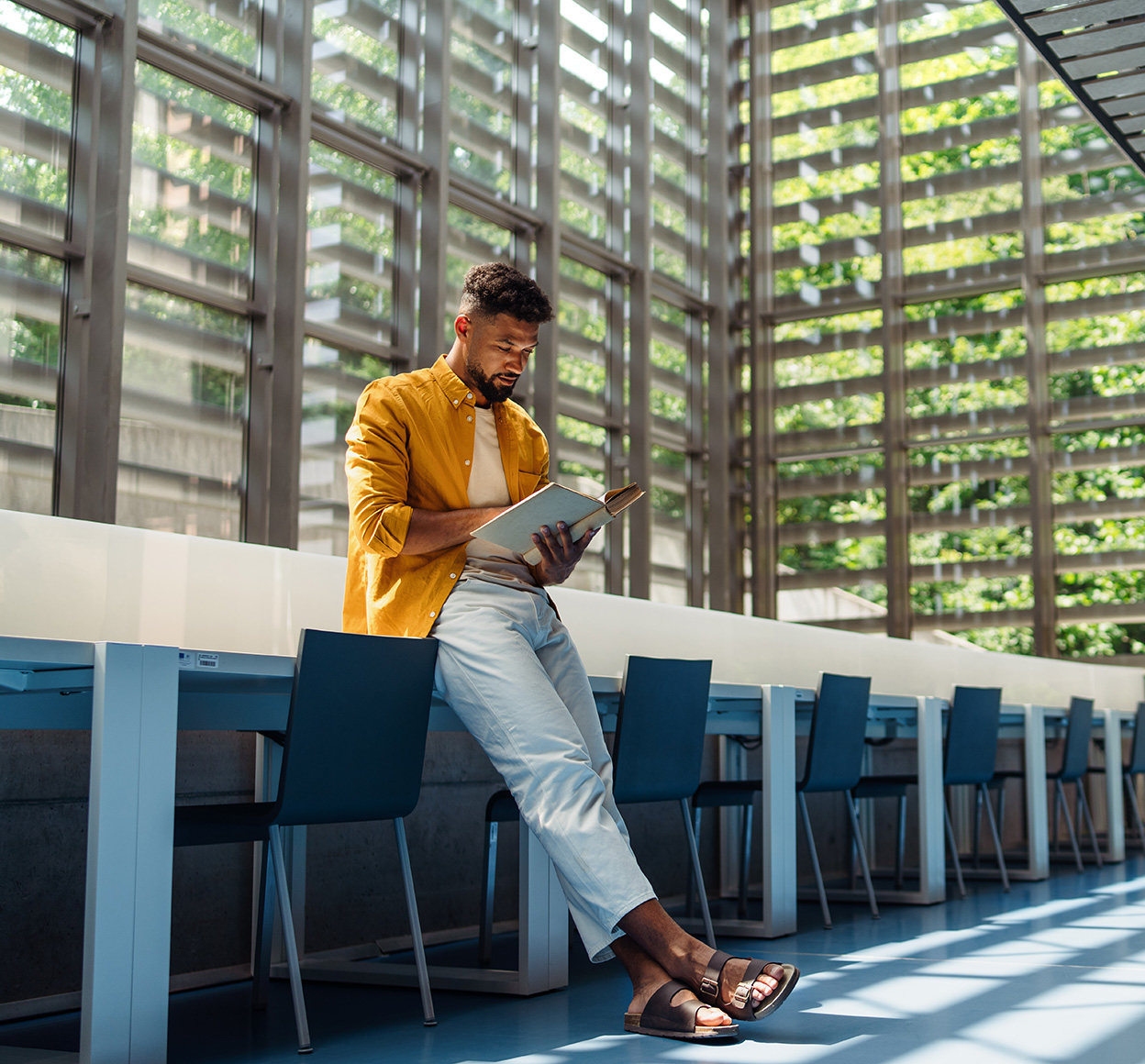 Young university student with book indoors in library reading