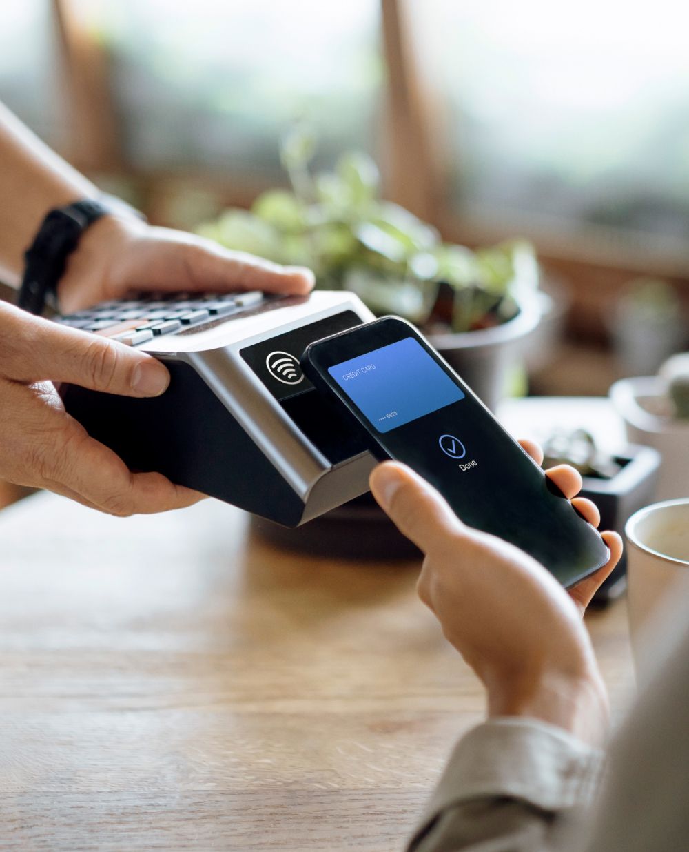 Cafe barista holds up a point of purchase device for a customer.