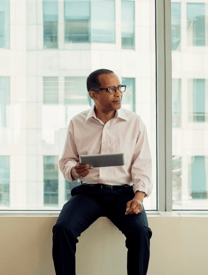 Photo of a man with a tablet sitting at a window