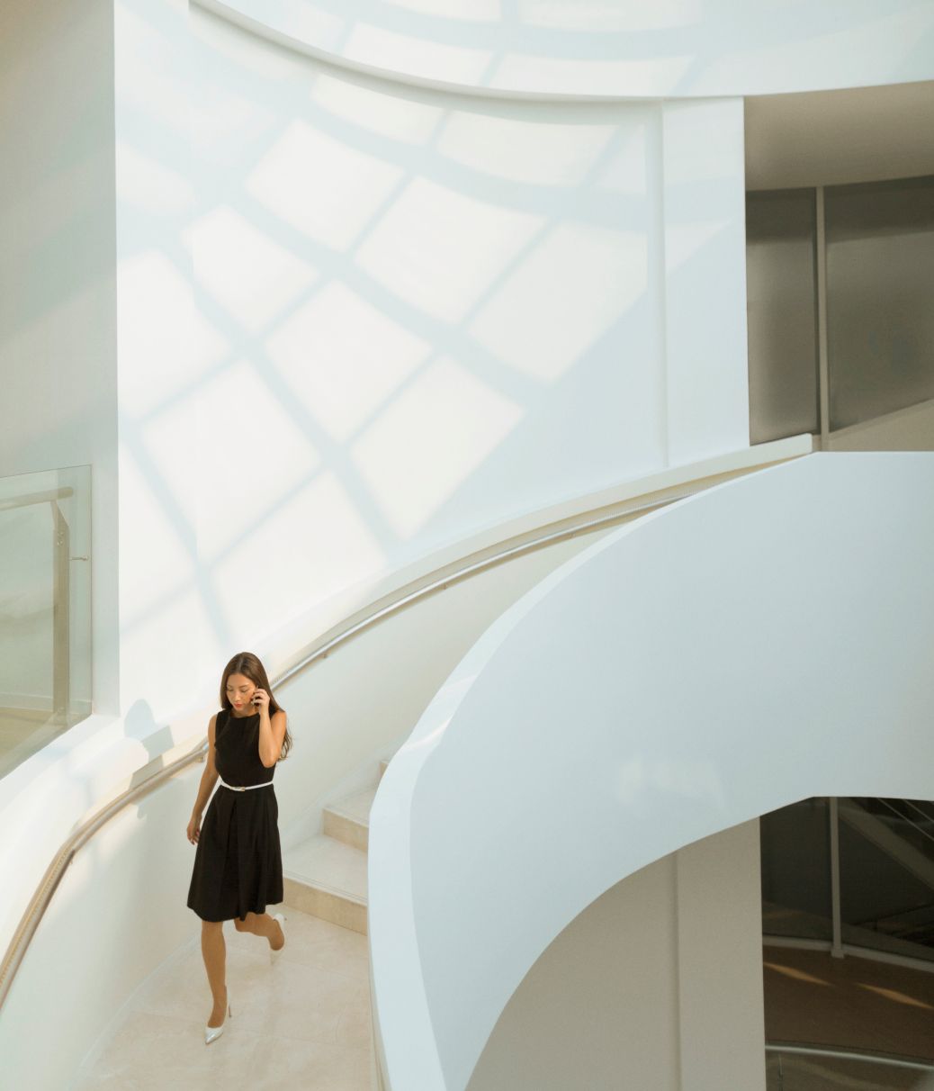 Woman with a cell phone climbing down a set of stairs in an office building